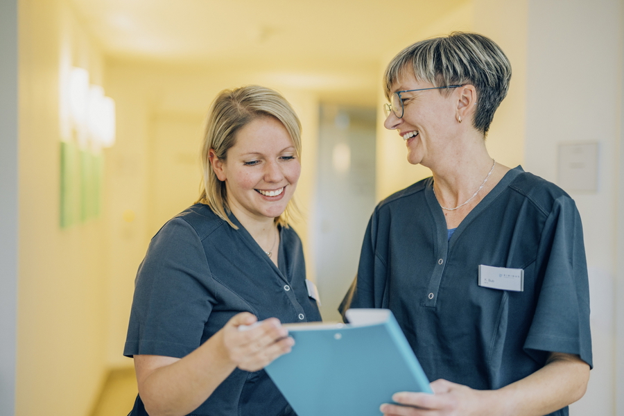 Zwei Mitarbeitende aus Pflege besprechen gemeinsam Unterlagen.