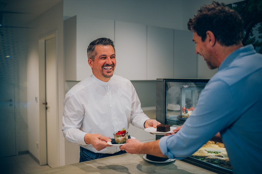Küchenmitarbeiter überreicht einem Gast einen Teller mit Kuchen.