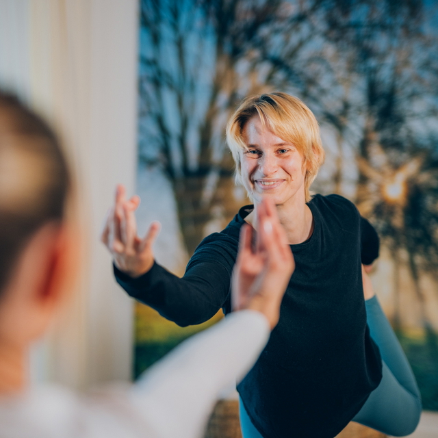 Körper- und Bewegungstherapeutin in einer Übung mit einer Person in einem Therapieraum.