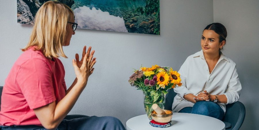 Zwei Frauen unterhalten sich an einem Tisch über die Ursachen der Ess-Brech-Sucht