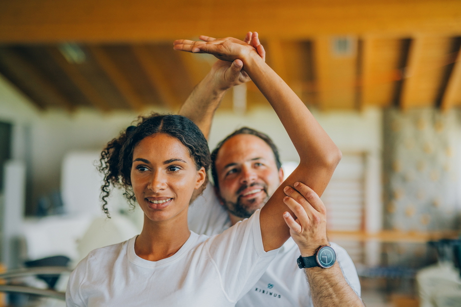 Physiotherapeut und Patientin führen gemeinsam eine angeleitete Bewegungsübung durch.