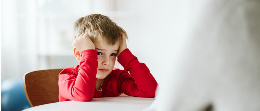 Ein Kind mit ADHS sitzt an einem Tisch 