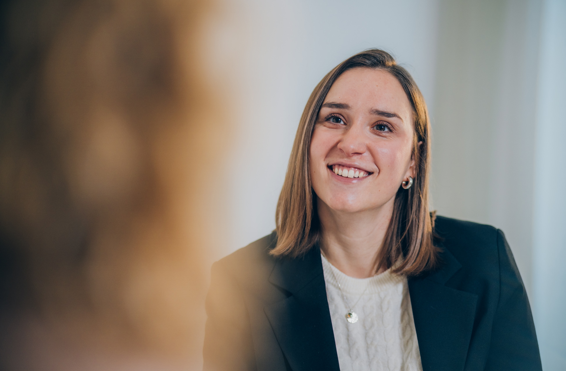 Eine Frau sitz in einem modernen Büro und lächelt eine Frau gegenüber an.
