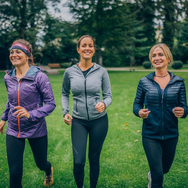 Drei Frauen joggen gemeinsam durch einen Park.