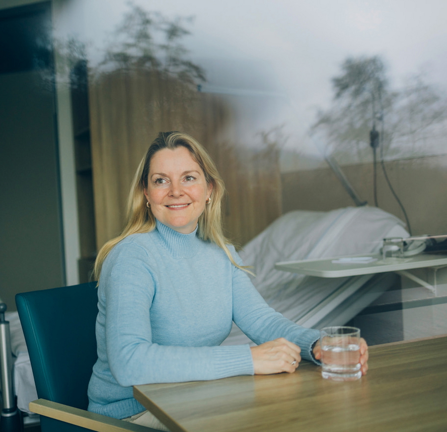 Patientin sieht lächelnd aus dem Fenster während ihres stationären Aufenthalts zur Bienengift-Hyposensibilisierung.