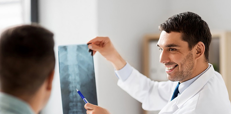 Ein Orthopäde betrachtet das Röntgenbild eines Patienten in Skoliose-Therapie