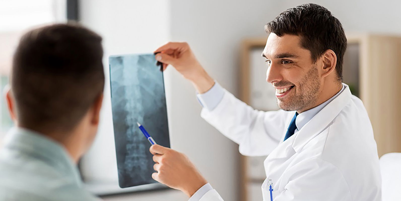 Ein Arzt bespricht nach der Frakturbehandlung ein Röntgenbild