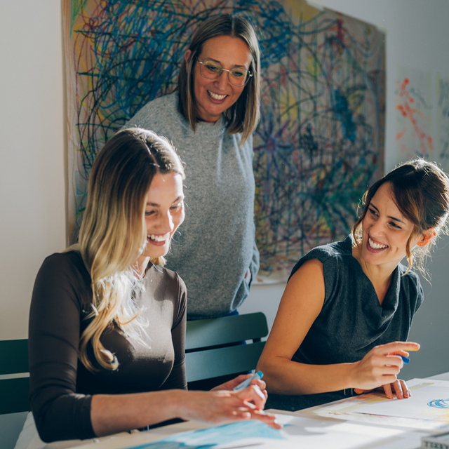 Drei Frauen im freundlichen Gespräch im Kunsttherapie-Raum.