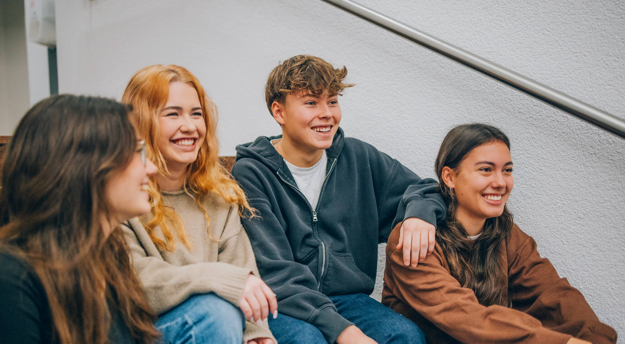 Kinder und Jugendliche sitzen auf der Treppe bei KIRINUS
