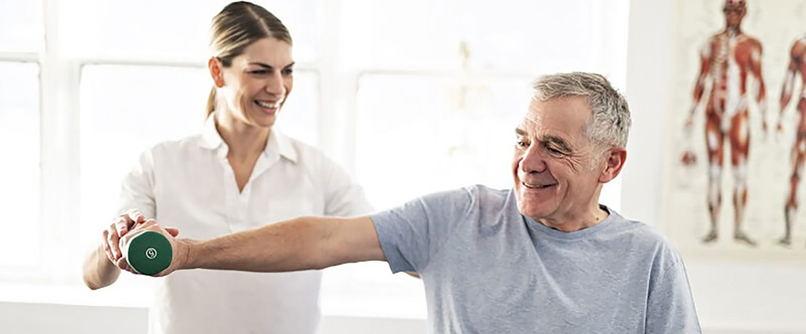 Physiotherapeutin hilft Patienten bei einer Übung mit Gewicht während der Reha nach einer Bandscheiben-OP