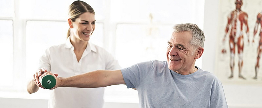 Physiotherapeutin hilft Patienten bei einer Übung mit Gewicht während der Reha nach einer Bandscheiben-OP