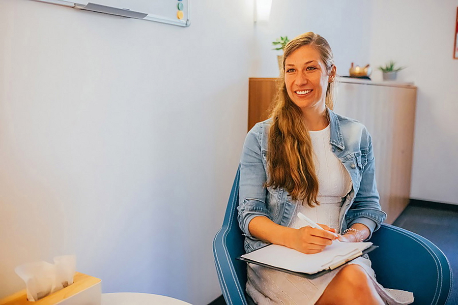 Weibliche Person sitzt auf einem Stuhl mit einem Klemmbrett in der Hand