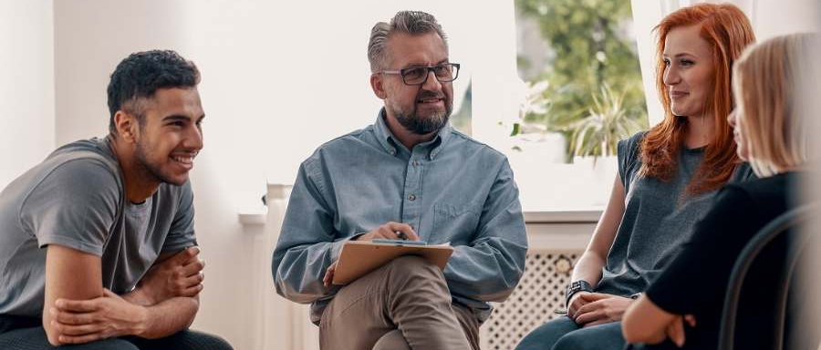 Drei Patienten mit Suchterkrankungen und ein Psychotherapeut in der Gruppentherapie