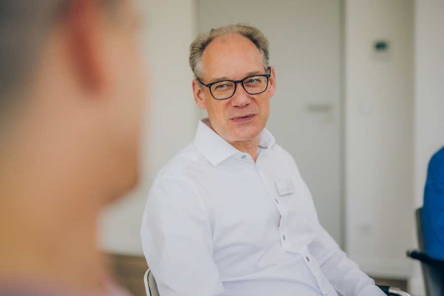 Arzt der Psychosomatik im weißen Hemd im Gespräch mit einer Patientin.