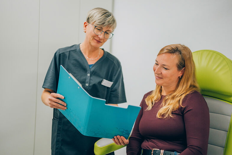 Medizinische Fachangestellte erklärt Patientin die Ergebnisse und den Ablauf der Bienengift-Hyposensibilisierung anhand der Patientenakte.