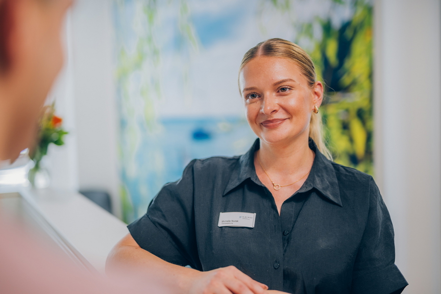 Mitarbeiterin im Patientenservice im Gespräch mit einer Person.
