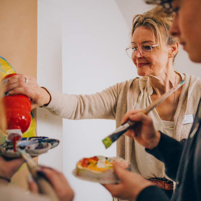 Therapeutin und zwei Jugendliche gestalten gemeinsam ein Kunstwerk.