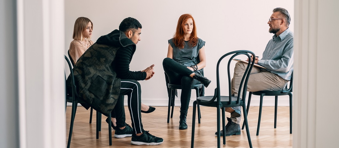 Vier Personen sitzen in einer Gruppentherapie zur Suchtbehandlung