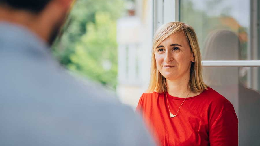 Gespräch zwischen zwei Personen am Fenster mit Blick in die Natur