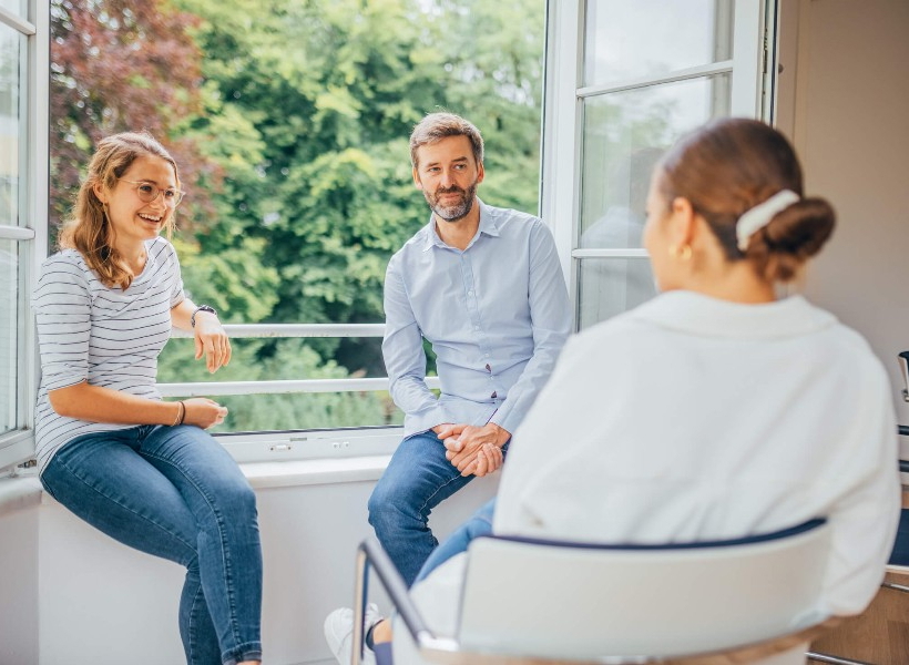 Drei Personen unterhalten sich am offenen Fenster