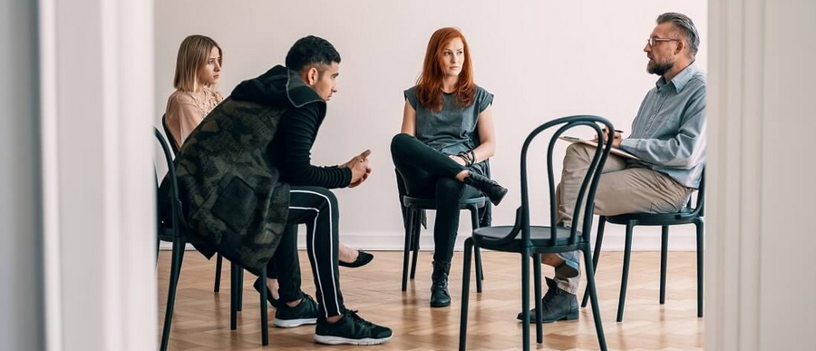 Vier Personen sitzen in einer Therapiesitzung zur Burnout-Therapie