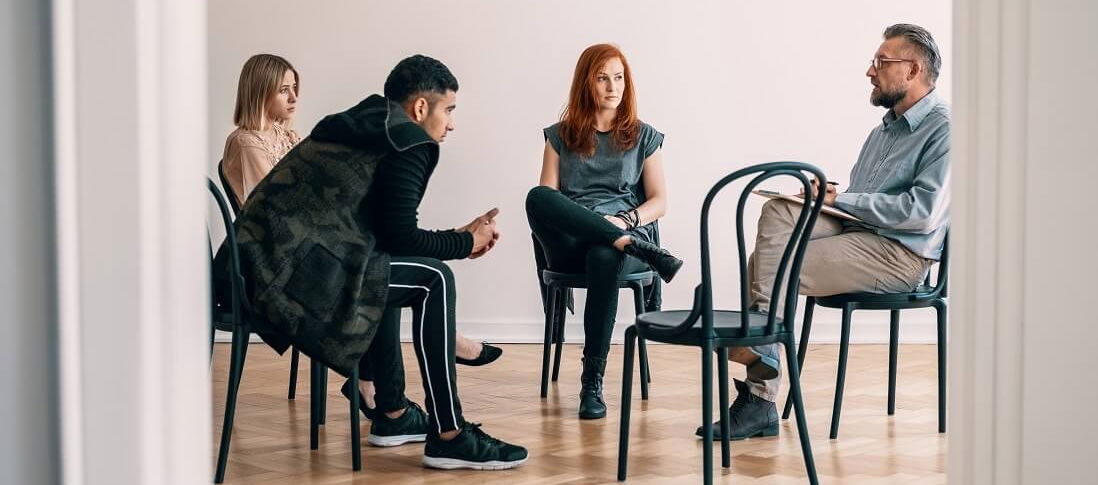 Vier Personen auf Stühlen bei der Medikamentensucht-Therapie