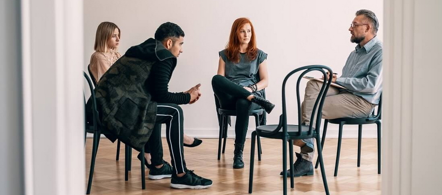 Vier Personen auf Stühlen bei der Medikamentensucht-Therapie