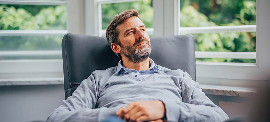 Männliche Person auf einem Sessel vor dem Fenster