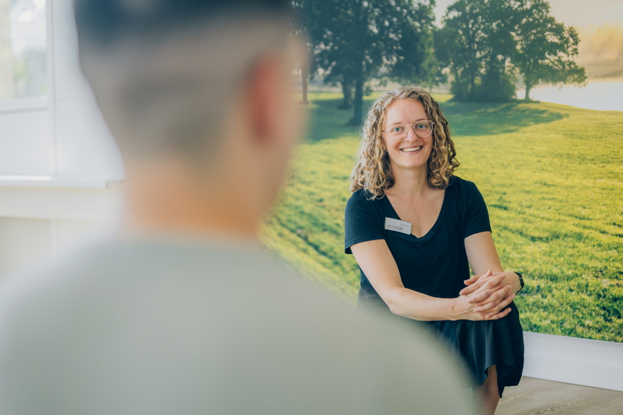 Körper- und Bewegungstherapeutin im Gespräch mit einer Person in einem Therapieraum.