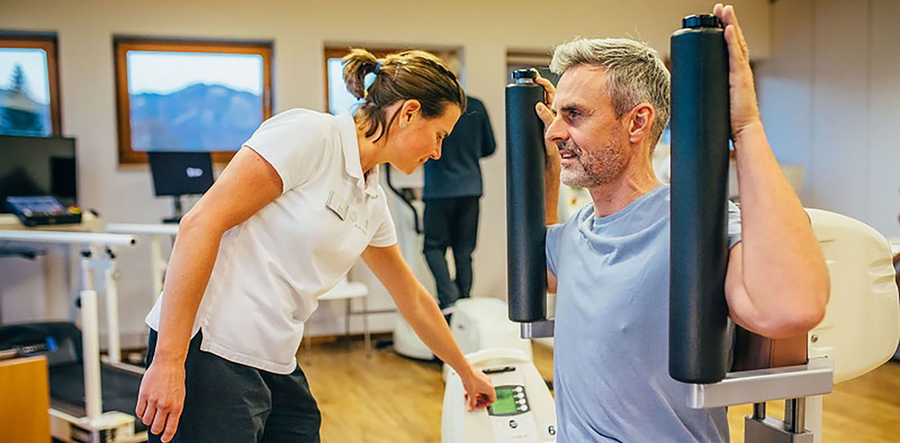 Patient trainiert im Fitnessraum als Bestandteil der Rückenschmerz-Therapie