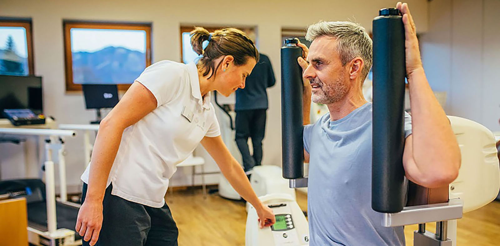 Patient trainiert im Fitnessraum als Bestandteil der Rückenschmerz-Therapie