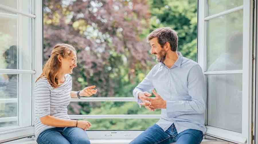 Zwei Personen unterhalten sich am offenen Fenster
