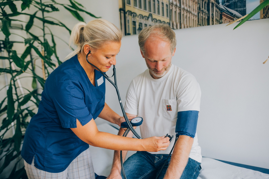 Medizinische Fachangestellte misst den Blutdruck eines Patienten.