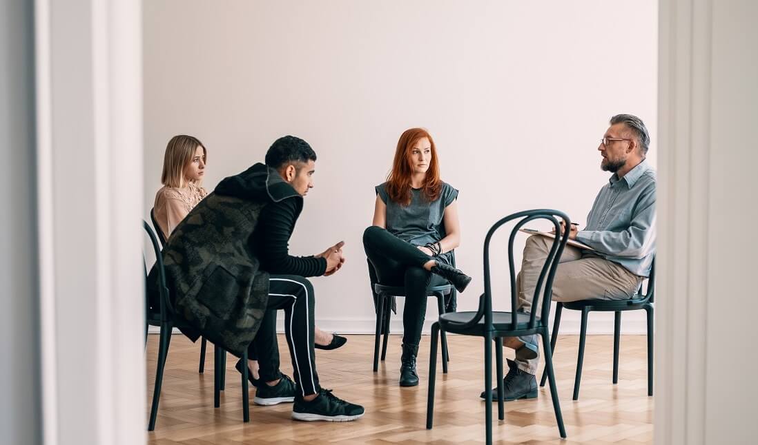 Vier Personen sitzen in einer Therapiesitzung zur Burnout-Therapie