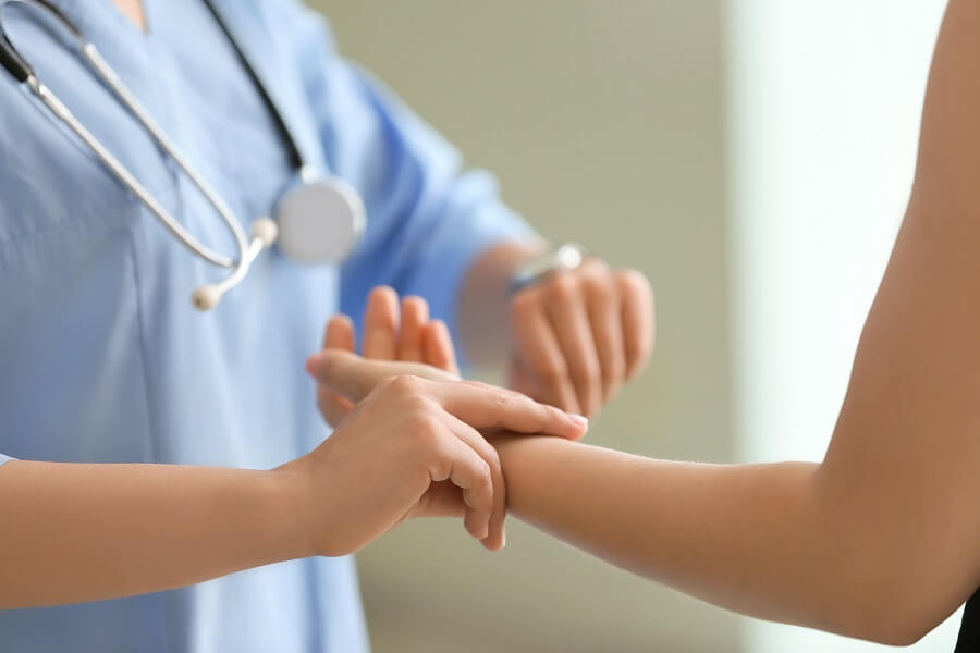 Eine Herzspezialistin der Kardiologie-Reha misst den Puls einer Patientin