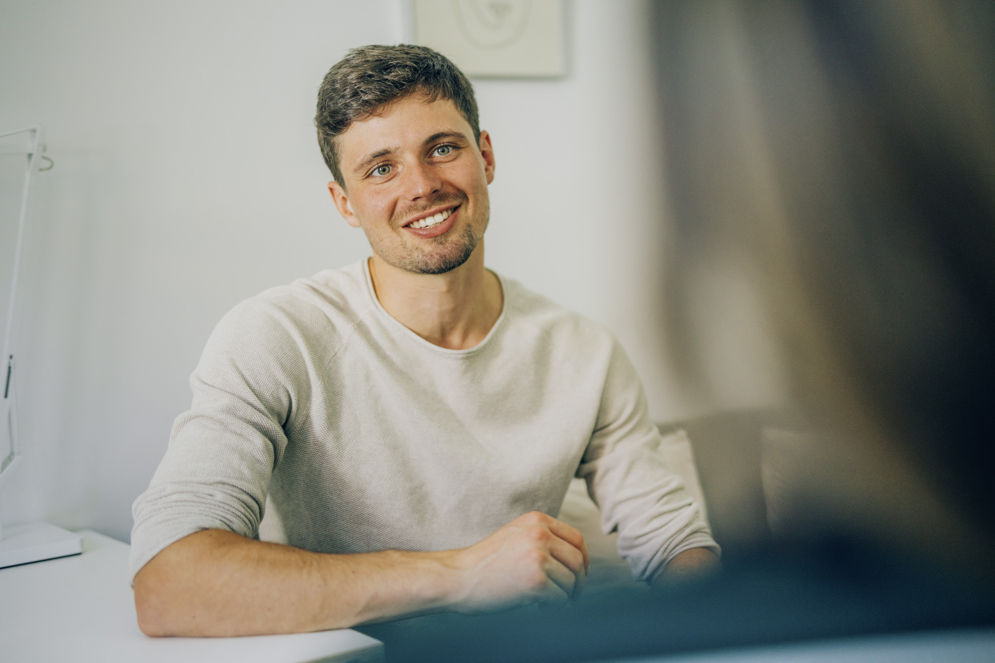 Mann sitzt im Gespräch an einem Tisch und blickt aufmerksam sein Gegenüber an – Darstellung einer Beratungssituation zur Depression erkennen.
