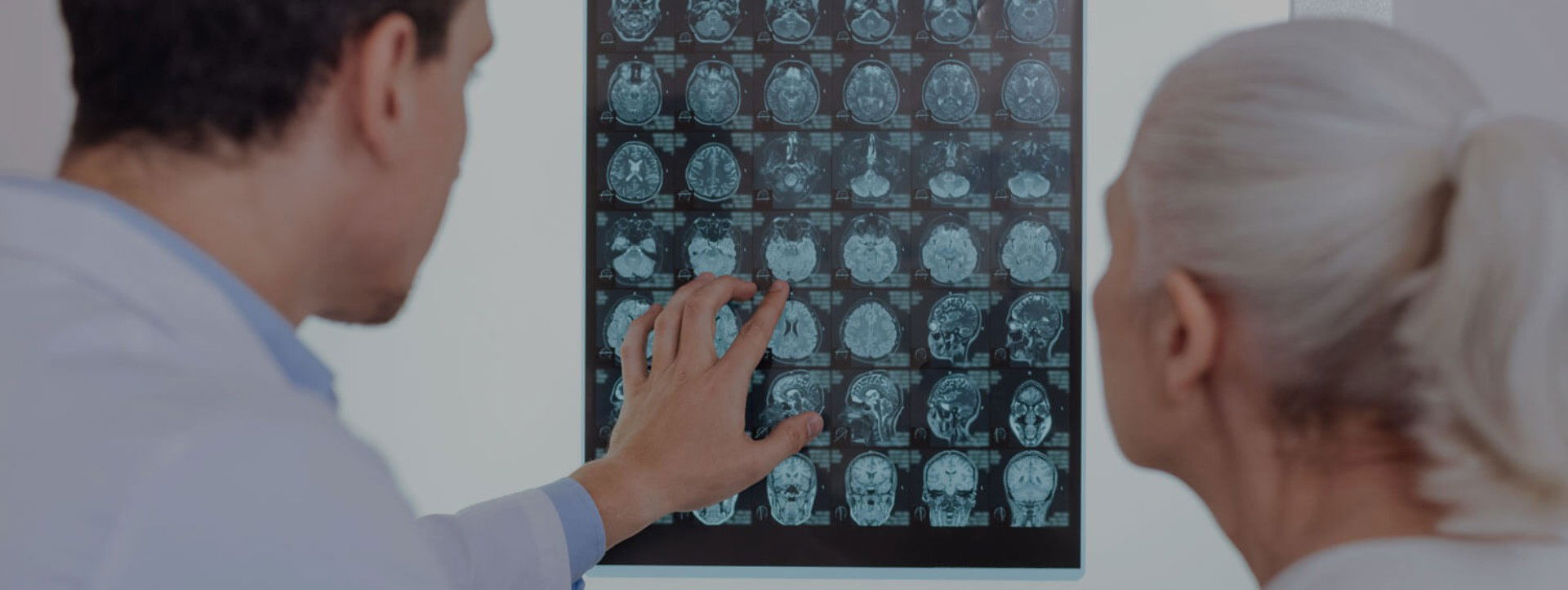 Neurologe und Patientin stehen vor dem Röntgenbild des Gehirns