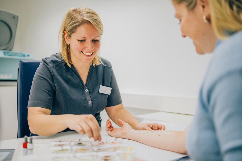 Medizinische Fachangestellte führt Allergietest am Unterarm einer Patientin zur Vorbereitung auf Hyposensibilisierung mit Bienengift durch.