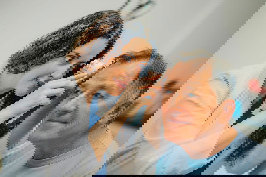 Ärztin untersucht die Haut im Gesicht eines Mannes