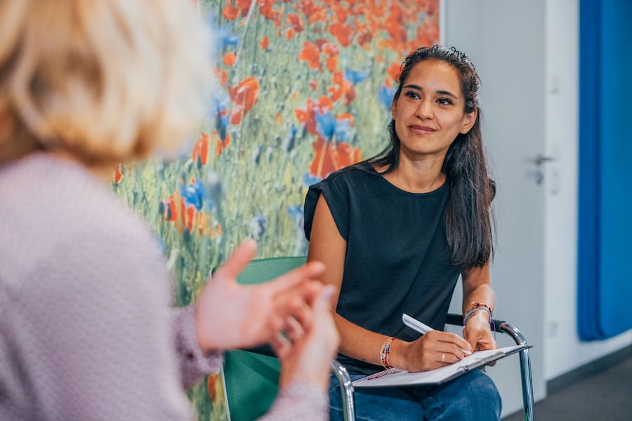 Therapeutin mit Klemmbrett auf dem Schoß während der Psychotherapie mit ihrer Patientin.