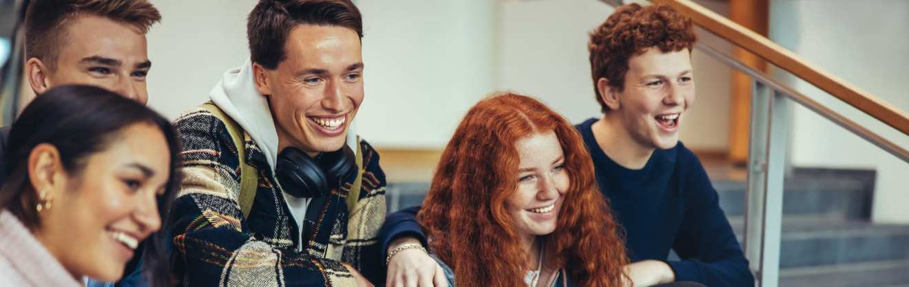 Kinder und Jugendliche sitzen auf der Treppe bei KIRINUS