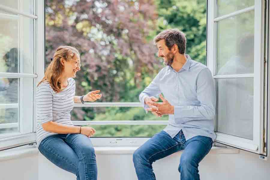 Zwei Personen unterhalten sich am offenen Fenster