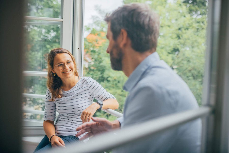 Zwei Personen unterhalten sich am offenen Fenster