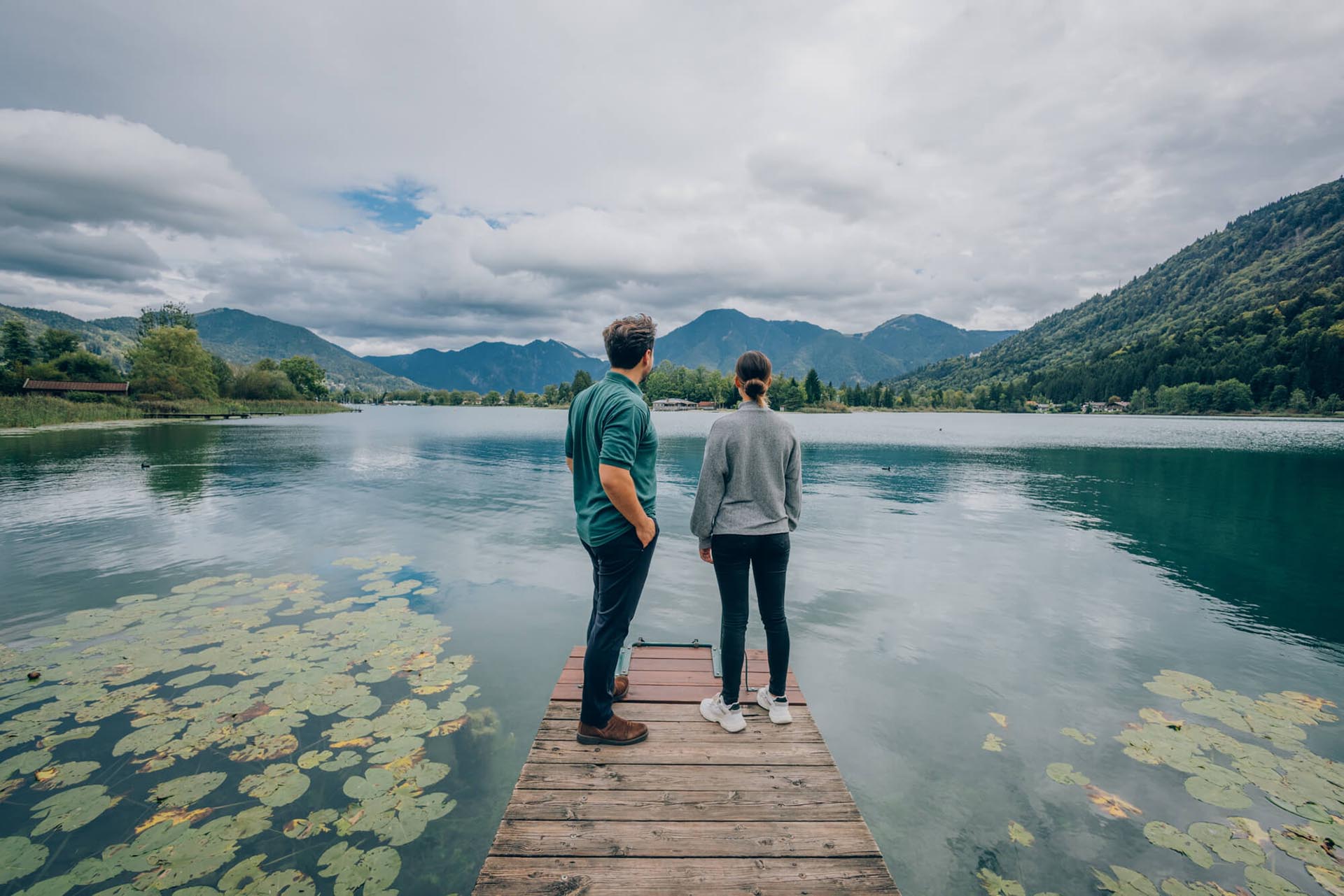 Zwei Personen stehen auf dem Steg mit Blick auf den Tegernsee und das Bergpanorama