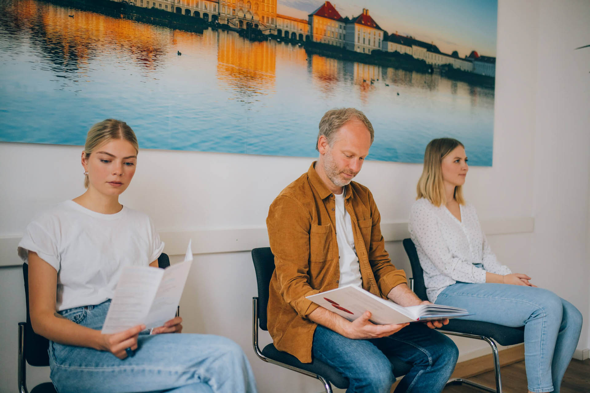 Drei Personen sitzen im Wartezimmer