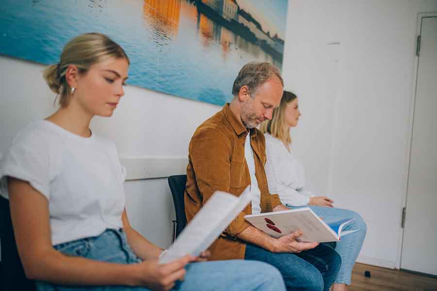 PatientInnen sitzen im Wartezimmer und lesen Zeitschriften