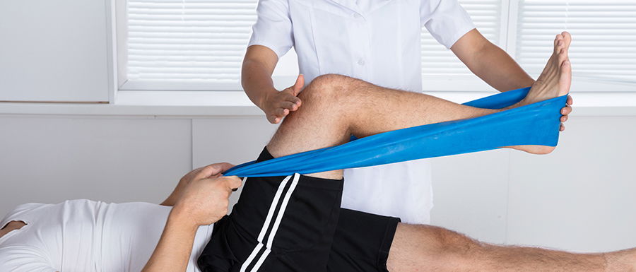 Physiotherapeut hilft einem Patienten bei einer Thera-Band-Übung nach einer Sprunggelenk-OP