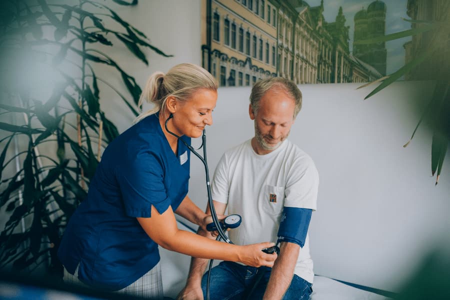 Medizinische Fachangestellte misst den Blutdruck eines Patienten.
